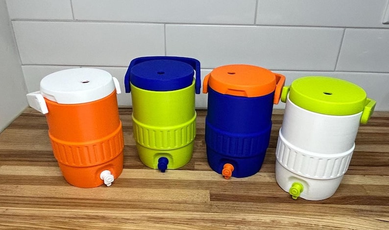 May include: Four colorful water coolers in orange, green, blue, and white, each with a matching lid and spigot. The coolers are cylindrical with a ribbed design around the base and a handle on top. They are arranged on a wooden surface.