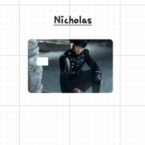 May include: A card with the name "Nicholas" in black script. The card features a person in a black military-style jacket with silver buttons and chain detail. The background is a blurred outdoor scene.