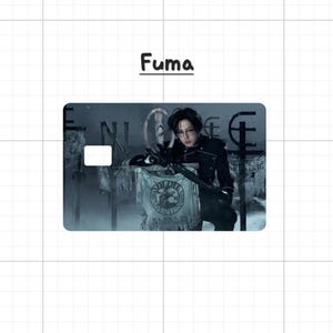 May include: A credit card featuring an image of a person in a black uniform, with the name "Fuma" above. The card has a white rectangle for a chip and a design of a banner with a crest.