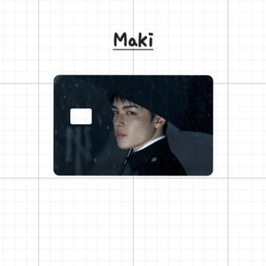 May include: A rectangular card with a portrait of a person holding an umbrella in the rain. The card has a white rectangle on the left side. The word "Maki" is written above the card in black.