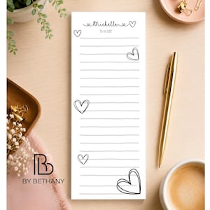 May include: A white rectangular to-do list notepad featuring black horizontal lines and hand-drawn heart illustrations. The top of the page displays the name Michelle in cursive script followed by the text TO DO LIST in a simple font.