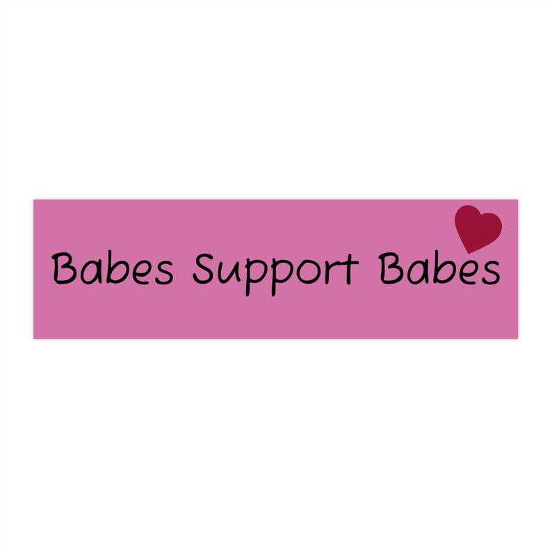 May include: A rectangular pink sticker with the words "Babes Support Babes" in black script. A red heart is in the upper right corner. The sticker is against a white background.