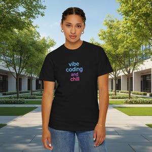Puede incluir: Camiseta negra con las palabras "vibe coding and chill" en un degradado de azul a rosa. La persona lleva vaqueros azules. El fondo muestra un edificio y árboles.