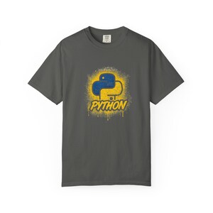 May include: Dark gray t-shirt featuring a blue and yellow Python logo design. The logo has a spray paint effect with the word "PYTHON" in a matching font. The shirt is a short-sleeved crew neck.