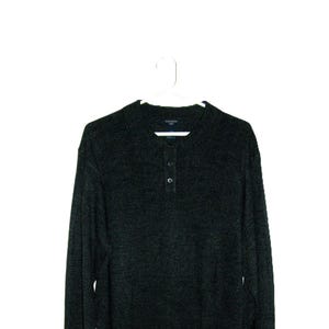 May include: Dark gray long-sleeved sweater with a crew neck and three-button placket. The sweater is hanging on a white hanger against a white background. The sweater appears to be made of a soft, textured material.