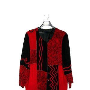 May include: A red and black patterned jacket with a button closure. The jacket is made of a soft, textured fabric.