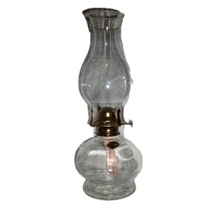 May include: A clear glass oil lamp featuring a rounded base and a tall, bulbous chimney. The lamp includes a metallic gold-toned burner assembly with a small adjustment knob on the side and a visible wick extending into the glass reservoir.