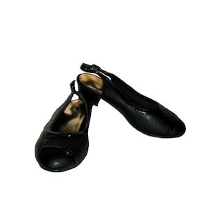 May include: A pair of black leather heeled slingback shoes with a gold buckle detail.
