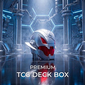 May include: A silver-colored TCG deck box shaped like a robotic head with red eye-like accents. The box features a metallic finish and is positioned in a futuristic setting with mechanical arms. The text PREMIUM TCG DECK BOX is printed below.