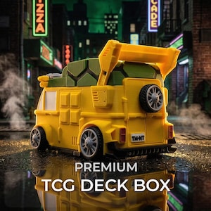 May include: A yellow and green plastic deck box shaped like a stylized van with a turtle shell roof, a rear-mounted spare tire, a spoiler, and a license plate reading TM-NT. The box features detailed wheels and a textured shell pattern on top.