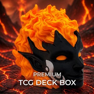 May include: A black and orange TCG deck box featuring a sculpted face with pointed ears and glowing orange eyes, topped with a textured orange flame design. The text PREMIUM TCG DECK BOX is printed in white at the bottom of the object.