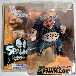 May include: A Spawn Reborn Clown IV action figure in original packaging. The figure has a red face with a wide grin, grey hair, a black jacket, a green and black striped shirt with the text BOO!, and blue jeans. The packaging includes Spawn branding.