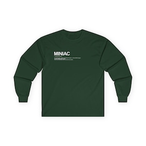 Könnte beinhalten: Ein dunkelgrünes Langarmshirt mit dem weißen Schriftzug "MINIAC", gefolgt von einer Definition im Wörterbuchstil. Die Grafik enthält die phonetische Aussprache und eine Beschreibung eines Enthusiasten des Mini Cooper oder des originalen Mini-Modells.