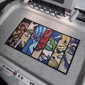 Może przedstawiać: Prostokątny wzór haftu składający się z siedmiu pionowych paneli przedstawiających stylizowane oczy w stylu anime w różnych kolorach, w tym czerwonym, niebieskim, zielonym i żółtym, wyszyty na jasnoszarej tkaninie w białym tamborku hafciarskim.