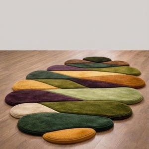 May include: A collection of oval-shaped rugs in various colors, including green, yellow, purple, and brown. The rugs are arranged in a flowing, layered pattern on a wooden floor, creating a modern and artistic design. The rugs vary in size.