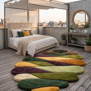 May include: An outdoor bedroom scene with a bed, pillows, and a patterned rug. The rug features a series of colorful, elongated shapes in shades of green, yellow, purple, and brown. The bed has a beige headboard and is covered with white linens.