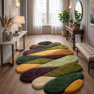 May include: A colorful, abstract area rug with a leaf-like design. The rug features sections of green, yellow, purple, and beige. The rug is placed on a hardwood floor in a well-lit hallway.