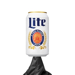 Puede incluir: Una lata de cerveza Miller Lite blanca con letras azules y doradas. La lata presenta las palabras "Lite" y "A Fine Pilsner Beer" con un diseño de trigo. La lata está parcialmente cubierta de gotas de agua.