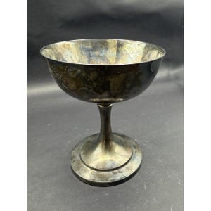 May include: A white ceramic mug with a black handle and the text "But First, Coffee" in a bold, black font. The mug is set against a blurred background, suggesting a cozy setting.