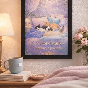 May include: A framed print featuring a cozy bedroom scene with three cats resting on a bed. The artwork has a soft, dreamy aesthetic with the text "Do not disturb - healing in progress." A teacup, books, and a small bowl are on a nightstand.