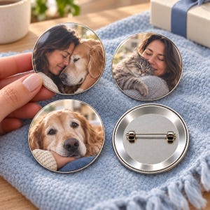 May include: Three circular pin-back badges featuring photographic prints and one badge showing the metallic back with a pin mechanism. Two badges display a person embracing a golden dog, and one badge shows a person embracing a tabby cat.