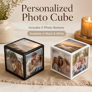 May include: Two square photo cubes, one with a black frame and one with a white frame, each displaying five different photographs on its sides and top. The text reads Personalized Photo Cube, Includes 5 Photo Buttons, Available in Black & White.
