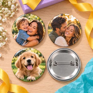 May include: Three circular pin-back badges featuring photographic prints. Two badges display smiling couples, and one badge shows a golden retriever puppy. The fourth badge is shown from the back, revealing a silver metal pin mechanism.