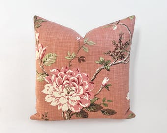 Könnte beinhalten: Ein rosa Kissen mit einem floralen Muster mit großen rosa und weißen Blüten mit grünen Blättern auf rosa Hintergrund.