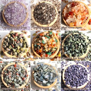 Pode incluir: Nove tigelas de madeira cheias de lascas de pedras preciosas. As tigelas contêm Light Amethyst, Smoky Quartz, Red Flower Agate, Dragon's Blood Stone, Jade Agate, Peacock Eye Stone, African Bloodstone, Nanhong Agate e Blue Goldstone.