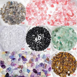 May include: An assortment of small, polished gemstones in various colors. The image displays seven different piles of stones, including gray, pink, clear, black, green, purple, and brown. Each pile is labeled with a number.