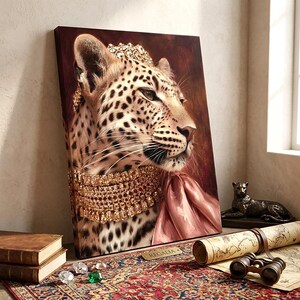 May include: A rectangular canvas print featuring a portrait of a leopard wearing a gold jeweled crown and a multi-layered gold necklace with a pink silk scarf. The leopard is depicted against a dark reddish-brown background with the word REGALIA.