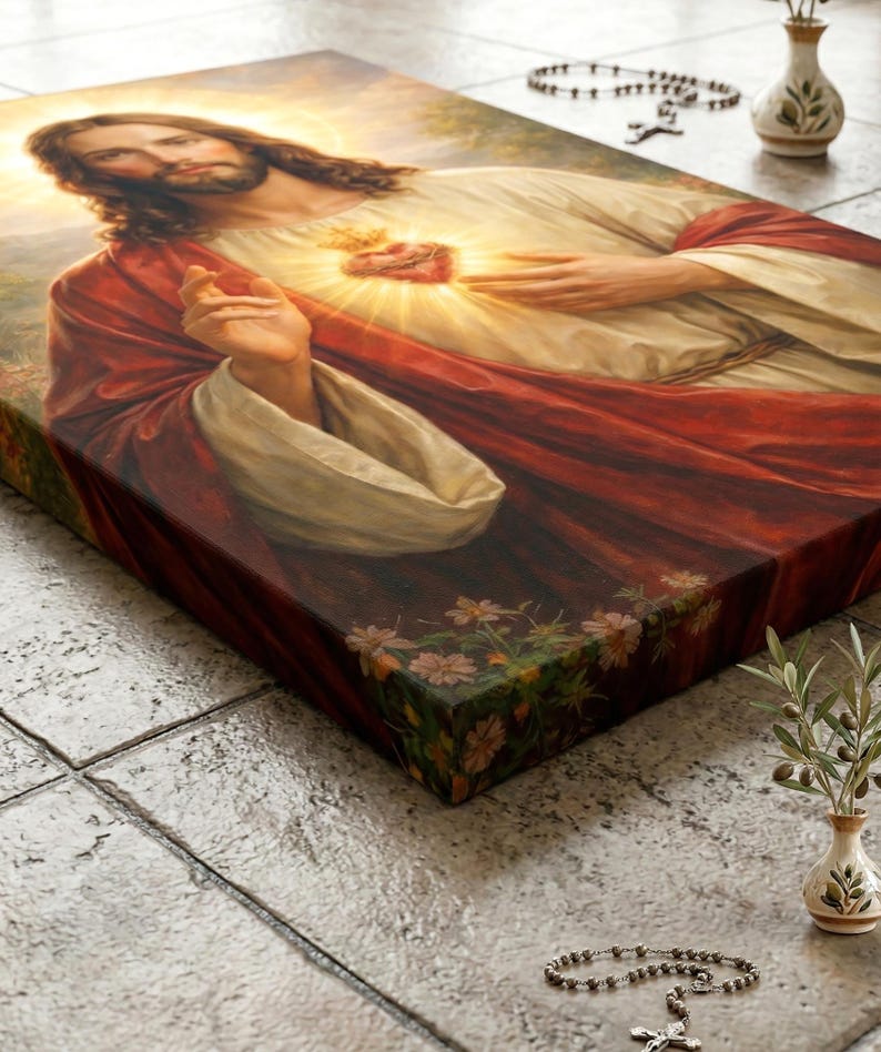 Peut inclure: Une impression sur toile religieuse repr&eacute;sentant J&eacute;sus avec un c&oelig;ur rayonnant, v&ecirc;tu d'une robe blanche et d'un manteau rouge. L'&oelig;uvre d'art est peinte en d&eacute;tail avec un &eacute;clairage doux et des motifs floraux sur le c&ocirc;t&eacute;. Un chapelet et un petit vase sont en arri&egrave;re-plan.