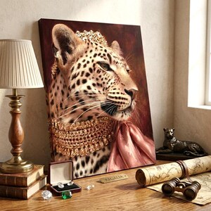 May include: A canvas print featuring a leopard wearing a gold crown and a multi-layered gold necklace with a pink fabric accent. The leopard is depicted in profile against a dark brown background. The artwork is titled Regalia on a small plaque.