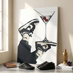 May include: A rectangular canvas print featuring a graphic illustration of a person wearing black and white sneakers, holding a martini glass with two red cherries on a toothpick. The artwork is displayed on a surface with black leather sneakers.