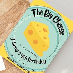 Puede incluir: Una invitación de cumpleaños amarilla con el texto "The Big Cheese" y "Johnny's 4th Birthday". La invitación presenta una cuña de queso de dibujos animados sobre un círculo azul claro. La invitación está en una bandeja de madera.