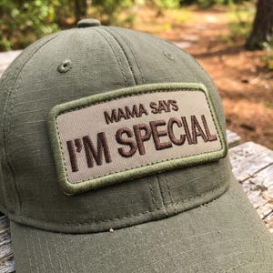 May include: A white ceramic mug with a black handle and the text "But First, Coffee" in a bold, black font. The mug is set against a blurred background, suggesting a cozy setting.