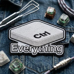 May include: Embroidered patch featuring a gray Ctrl key design with the word "Ctrl" in black, and the word "Everything" below it. The patch has a black border. Other keyboard components and tools are visible on a denim background.