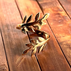 May include: A gold-toned ring with a leaf design. The ring is made of metal and has a twisted band.