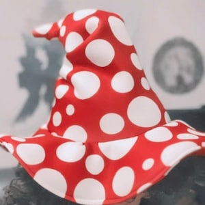 May include: A person wearing a red and white polka dot mushroom hat. The hat has a wide brim and a pointed top.