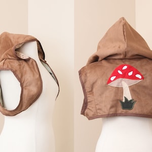 May include: A brown suede hooded vest with a red and white mushroom applique on the back.