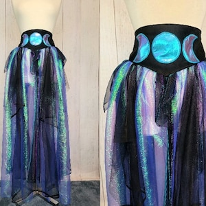 Puede incluir: Una falda de tul negra e iridiscente azul con una cintura de tela negra que presenta un diseño de triple luna. La cintura está decorada con tres formas de luna azul.