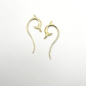 May include: A pair of gold-coloured earrings with a unique, curved design. The earrings are made of metal and have a delicate, flowing shape.