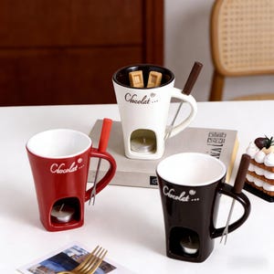 Può includere: Tre tazze da fonduta in ceramica rossa, bianca e nera, ciascuna con un portacandele, un manico e la scritta "Chocolat..." stampata sul lato. Ogni tazza include una piccola forchetta. La tazza bianca contiene quadratini di cioccolato.
