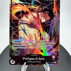 May include: A holographic One Piece trading card featuring Portgas D. Ace as a leader. The card displays a power level of 5000, a life value of 5, and text detailing game mechanics. The artwork shows a dynamic, colorful illustration of the character.