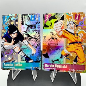 May include: Two rectangular trading cards featuring anime characters Sasuke Uchiha and Naruto Uzumaki. Each card displays a dynamic character illustration, manga-style panels, holographic gold accents, and text including character names and the word SAMPLE.