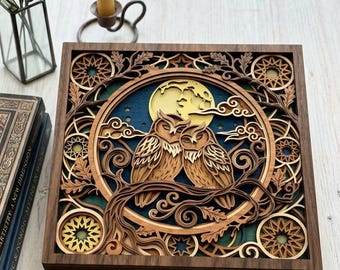 May include: A square, multi-layered wooden wall art piece featuring two owls perched on a branch against a full moon and a dark blue background. The frame is dark wood, and the intricate design includes laser-cut geometric patterns, oak leaves, and swirling branches in various shades of brown and tan wood tones.