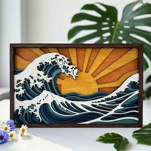 Puede incluir: Una pieza de arte mural rectangular de madera con un diseño en capas y multidimensional de una gran ola oceánica en tonos azules y blancos, sobre un fondo de sol amarillo y naranja, todo dentro de un marco de madera de color marrón oscuro.