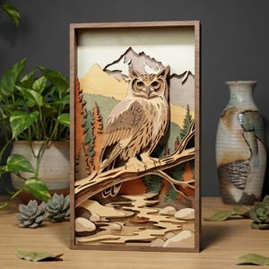 May include: A wooden layered art piece featuring an owl perched on a branch, set against a mountain and forest backdrop. The artwork uses natural wood tones and earth tones, creating a three-dimensional effect. The piece is framed in a dark wood.