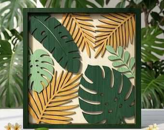 May include: A square wooden wall art piece featuring layered, laser-cut tropical leaf silhouettes in shades of dark green, light green, and mustard yellow, all set within a dark green frame against a light wood background.