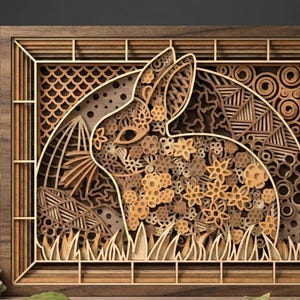 May include: A layered wooden art piece featuring a rabbit design. The artwork is framed in a dark wood and showcases a detailed silhouette of a rabbit filled with floral and geometric patterns. The rabbit is set against a backdrop of intricate designs.